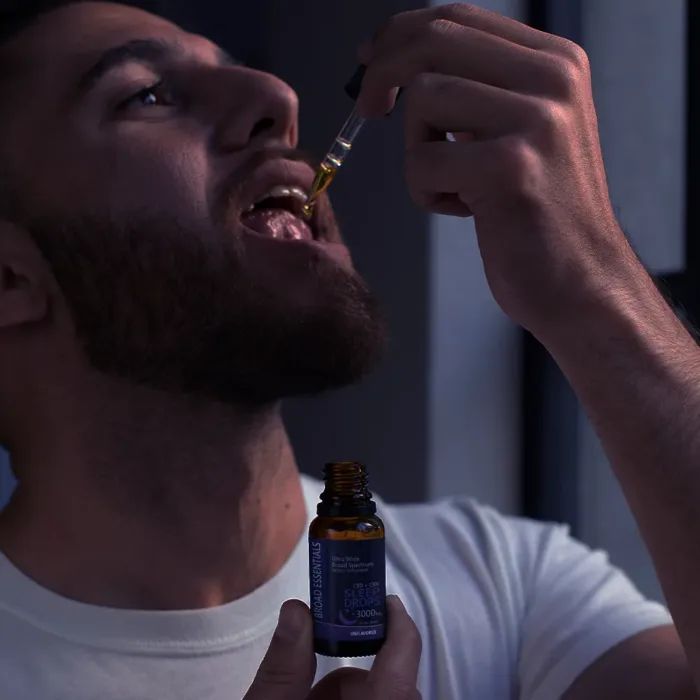 A man taking a CBD + CBN tincture for sleep.