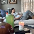 Man relaxing on a couch, featuring a CBD candle on a table next to him