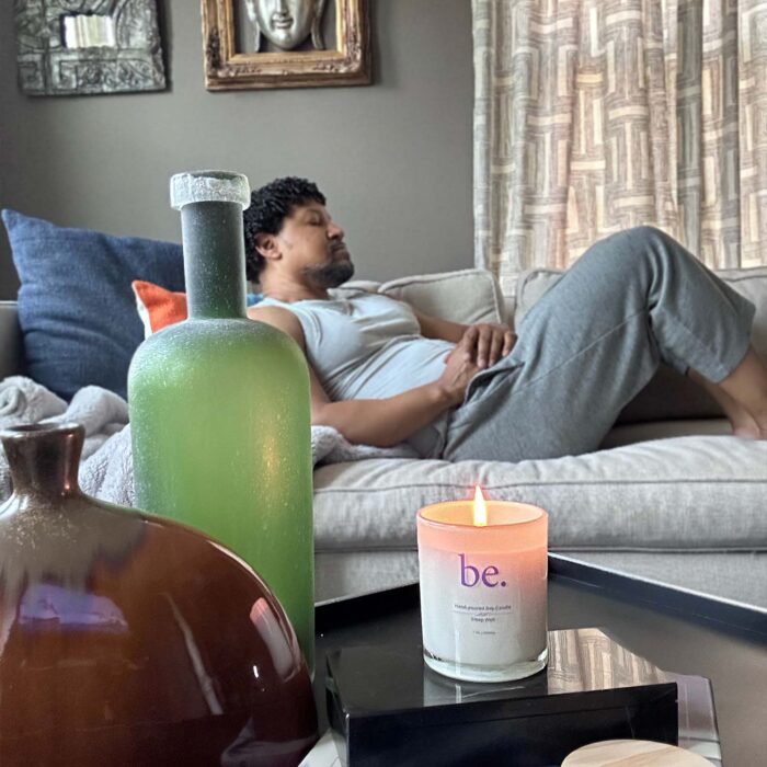 Man relaxing on a couch, featuring a CBD candle on a table next to him