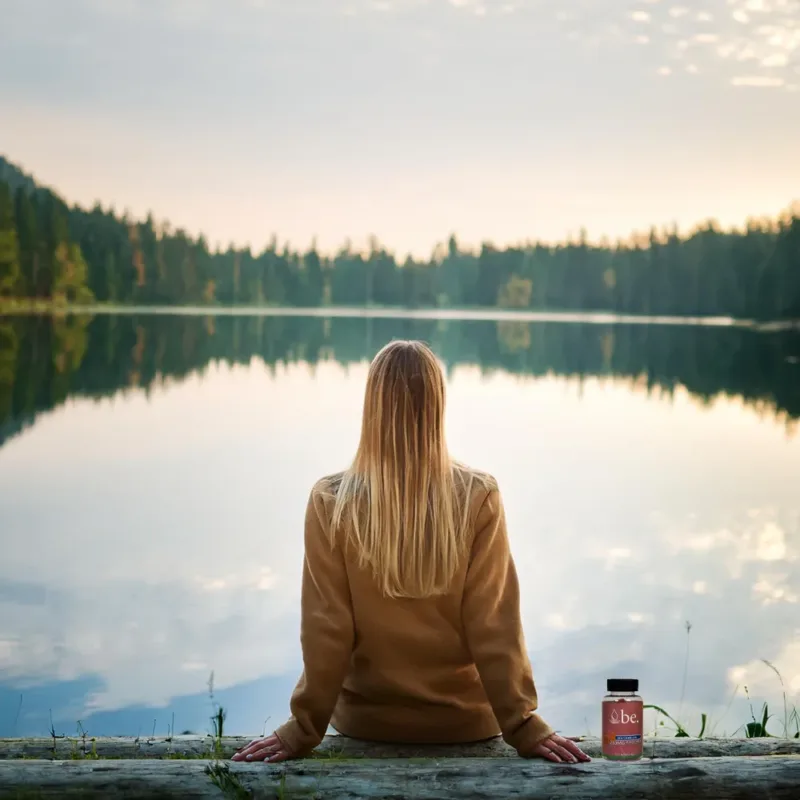 A woman overlooking a lake with CBD gummies by her side