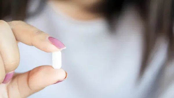 A woman holding a CBD capsule.