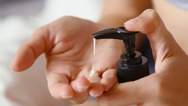 A woman pumping lotion into her hand.