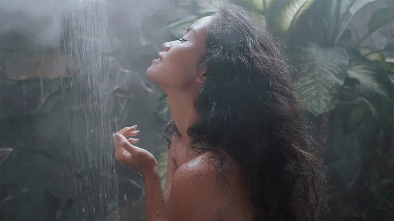 A woman taking a shower with a shower steamer.