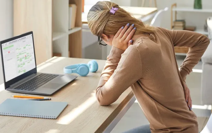 A woman sitting at a desk with back pain.