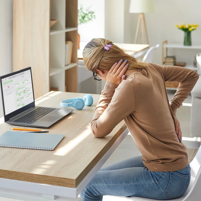 A woman sitting at a desk with back pain.