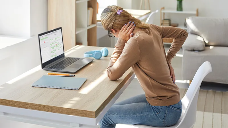 A woman sitting at a desk with back pain.